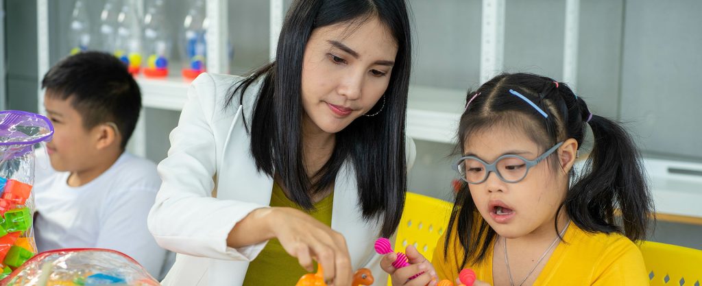 Image of a child care worker interacting with two children