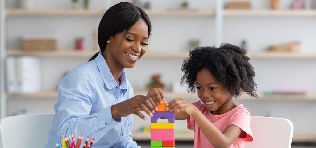 Black girl and child care worker playing with bricks
