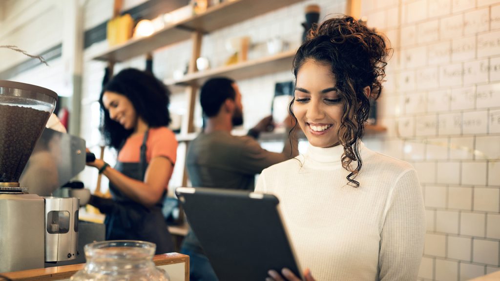Happy woman, tablet and small business at cafe in management, network or ownership at coffee shop. Female person, entrepreneur or restaurant owner smile with technology, team and barista in store