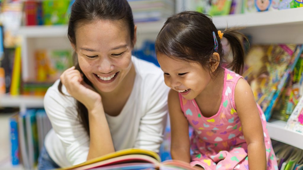 Parent and child reading books together in the library.